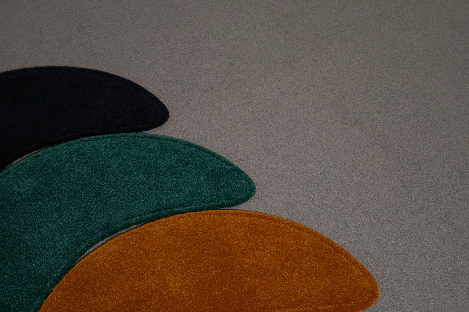 Black, green and orange rugs overlapping on a carpeted floor